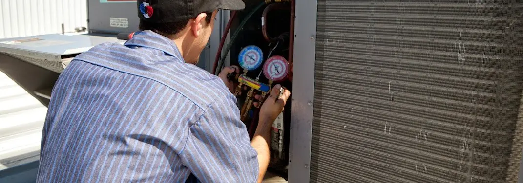 HVAC technician servicing a condenser unit in Lawndale